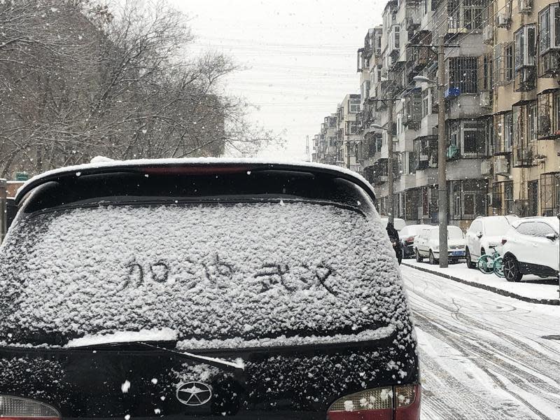 北京降大雪，路邊汽車車窗積雪被人寫上加油打氣的口號（東方IC）