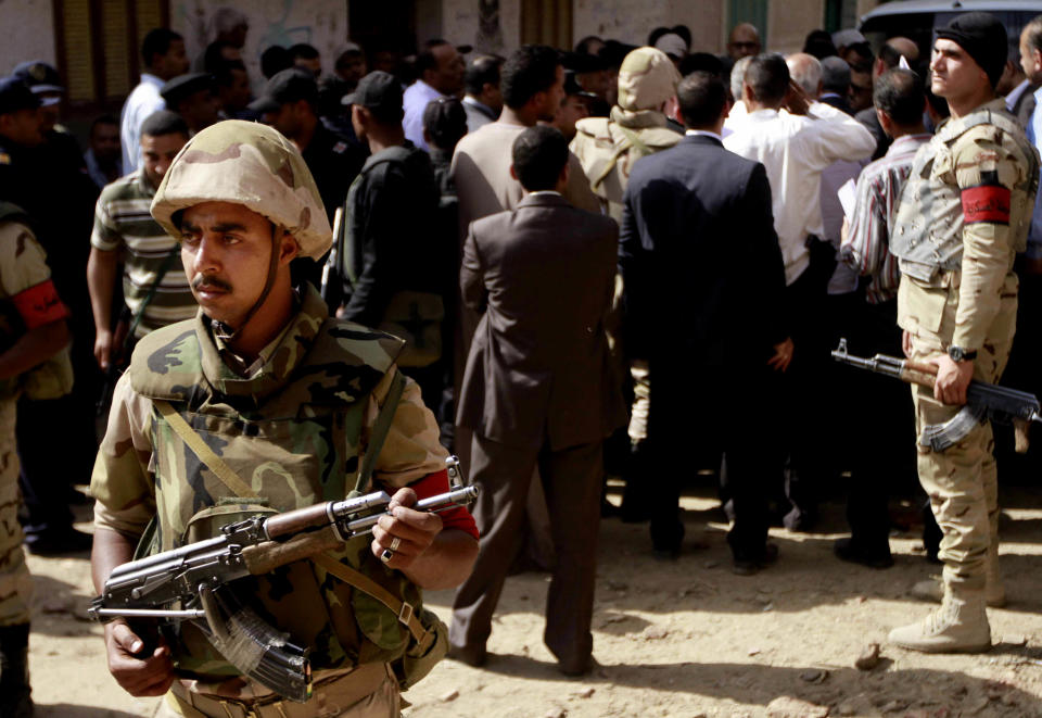 Egyptian military forces stand guard as Egyptian prosecutor general, Hisham Barakat, tours the area where fighting took place on Friday, April 4, between a Nubian family and members of the Arab Haleyla clan, in the southern city of Aswan, Egypt, Tuesday, April 8, 2014. Telephone and Internet networks were briefly shut down to Egypt’s southern province of Aswan for several hours, as authorities moved to try to end a bloody tribal feud that killed tens the past week, security officials and residents said Tuesday. (AP Photo/Sabry Khaled, El Shorouk Newspaper) EGYPT OUT