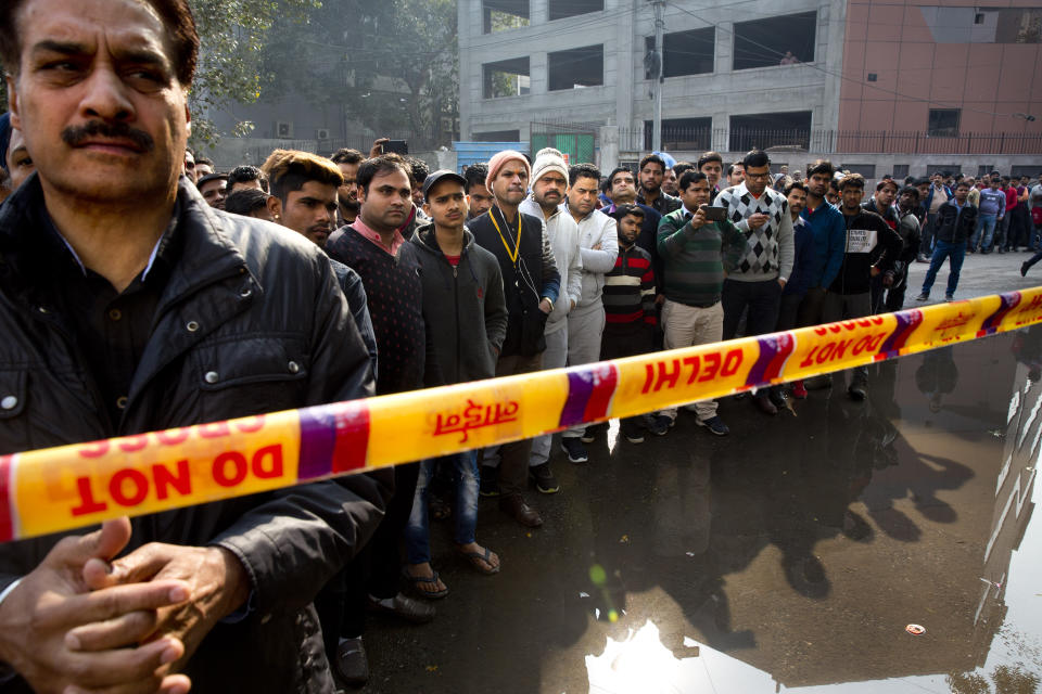 Onlookers gather after an early morning fire at a hotel killed more than a dozen people in the Karol Bagh neighborhood of New Delhi, India, Tuesday, Feb.12, 2019. (AP Photo/Manish Swarup)