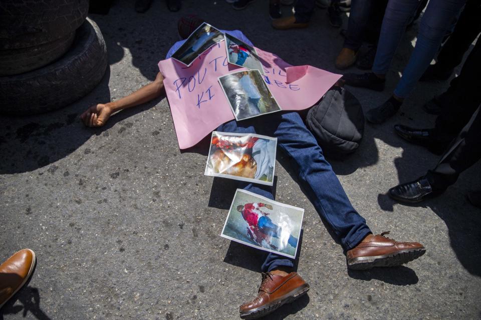 FILE - In this Sept. 1, 2020 file photo, a demonstrator lies on the pavement depicting the lifeless body of Bar Association President Monferrier Dorval, covered with photos of the murder scene, during a protest to demand justice for Dorval, who was fatally shot in his home, in Port-au-Prince, Haiti. Police statistics are unreliable, but authorities reported 1,380 killings in 2020, with the U.N. noting it was a 20% increase from the prior year. (AP Photo/Dieu Nalio Chery, File)