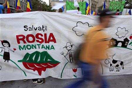 A man walks past a banner during a demonstration against the opening of the Rosia Montana open cast gold mine in Bucharest September 1, 2013. REUTERS/Radu Sigheti