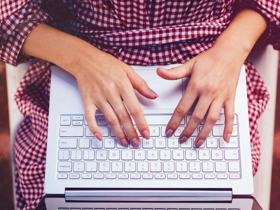 Woman sitting in chair writing emails on laptop