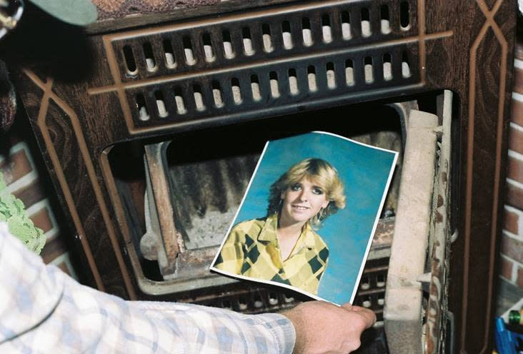 his undated photo provided by the Yavapai County Sheriff's Office shows a law enforcement official discovering a photograph of Pamela Pitts in the wood stove of a home she shared with two others in Prescott, Ariz., in 1988. Pitts' then-roommate, Shelly Harmon, recently confessed to killing Pitts and was sentenced to time she already had served in another killing. (Yavapai County Sheriff's Office via AP)