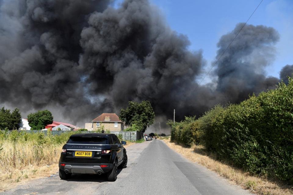 A car drives near a fire that burns during the heatwave, in Rainham, east London (Reuters)