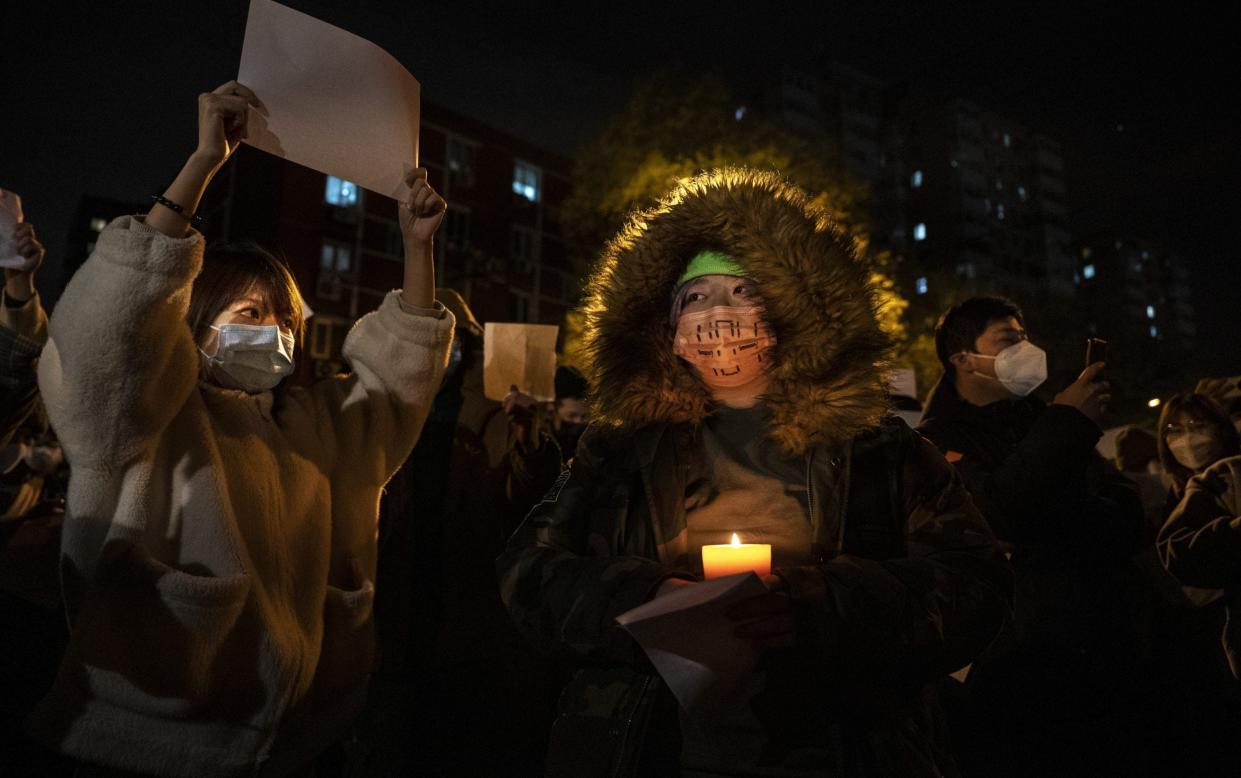 A protester holds a candle as another a white piece of paper against censorship during a protest against Chinas strict zero Covid measures - Kevin Frayer/Getty Images