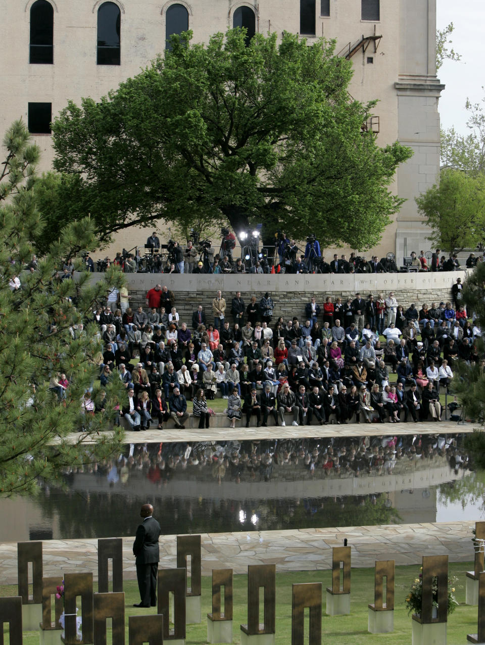 FILE - In this April 19, 2010 file photo, people gather under the Survivor Tree at the Oklahoma City National Memorial during a ceremony marking the 15th anniversary of the Oklahoma City bombing. As part of the city's annual day of remembrance Friday, April 19, 2019 – the 24th anniversary of the attack – civic leaders will plant a tree in a city park that was cloned from this scarred American elm that survived the deadliest act of domestic terrorism on U.S. soil. (AP Photo/Sue Ogrocki, File)