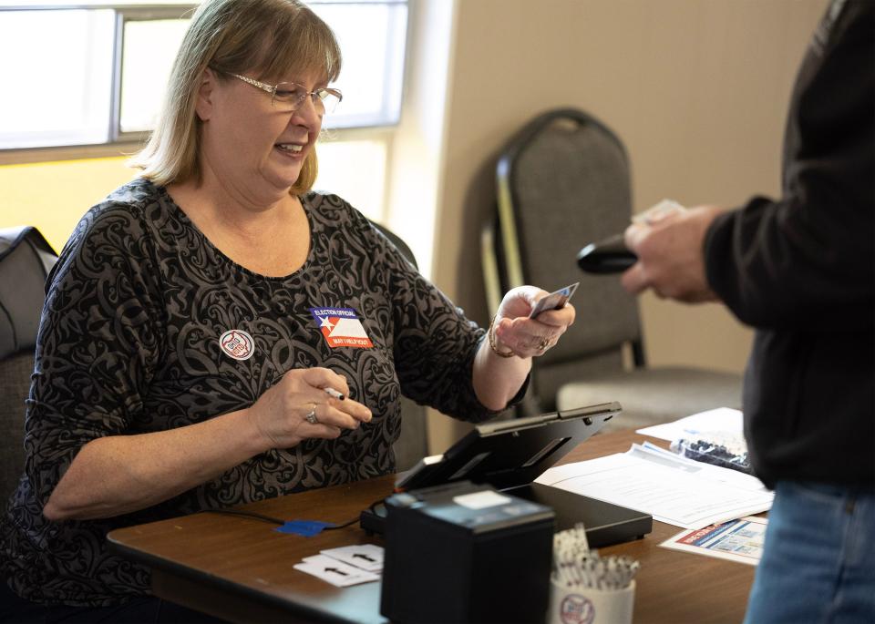 Poll worker Dorothy Schweitzer takes an Ohio ID from a voter Tuesday at Perry Baptist Church. Photo IDs are now required in Ohio to vote.