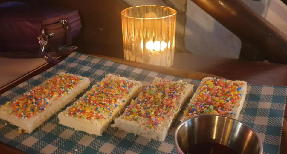 Pieces of fairy bread served on a wooden board. 
