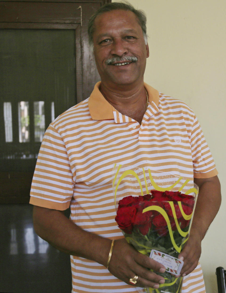 Former Indian Test cricketer and Board of Control for Cricket in India (BCCI) Vice-President Shivlal Yadav smiles as he accepts a bouquet of flowers at his residence in Hyderabad, India, Friday, March 28, 2014. India's Supreme Court ordered national cricket boss Narayanaswami Srinivasan to step aside on Friday until the completion of an investigation into corruption in the Indian Premier League (IPL). The court appointed test great Sunil Gavaskar as temporary president for the duration of the IPL and directed that the senior most Vice President of the Board, Yadav, will discharge the functions of BCCI president "with regard to all other matters," according to a local news agency. (AP Photo/Mahesh Kumar A.)