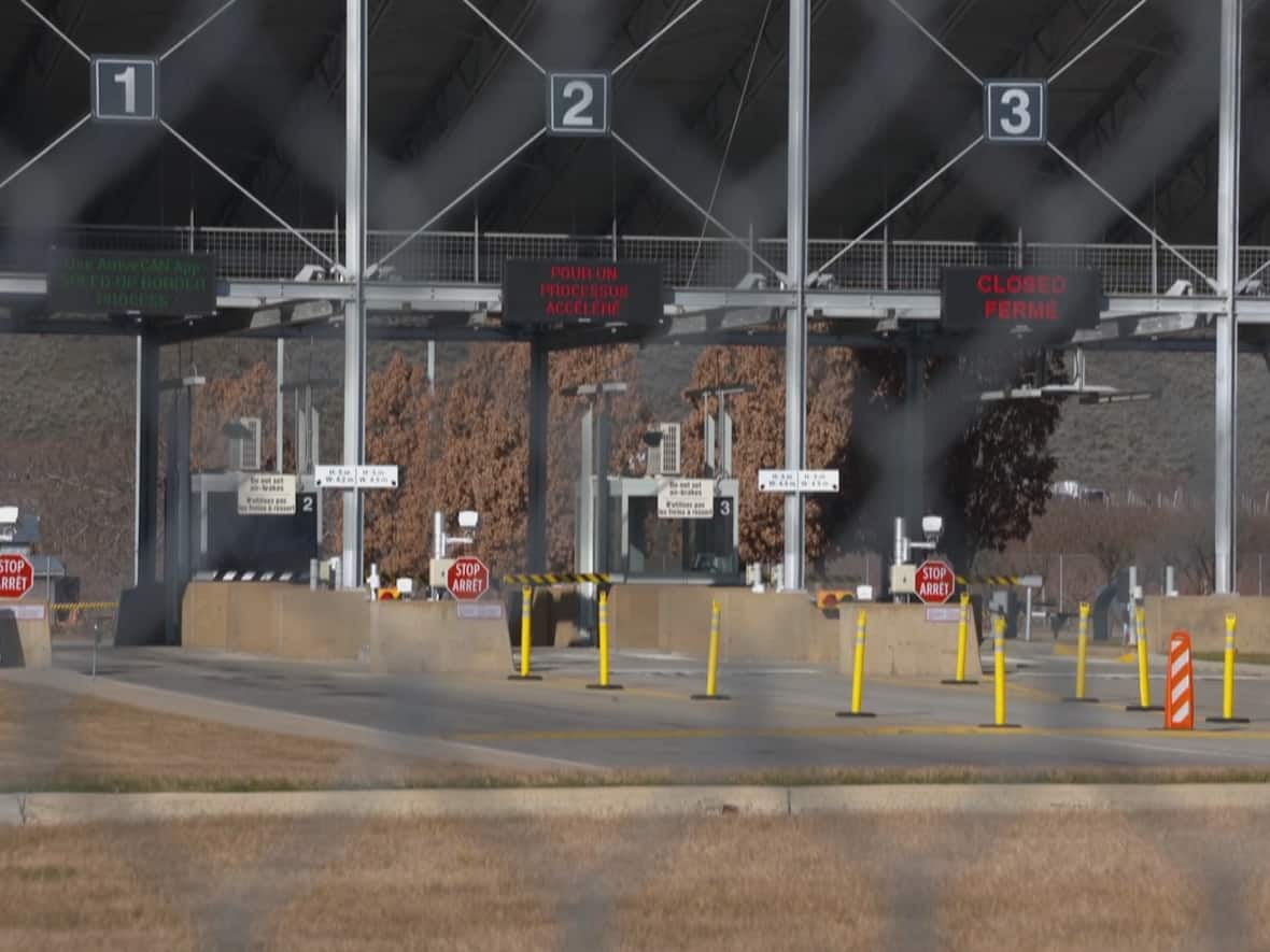 A view of the Oroville-Osoyoos border crossing through a chain-link fence on the Canadian side. (Curtis Allen - image credit)