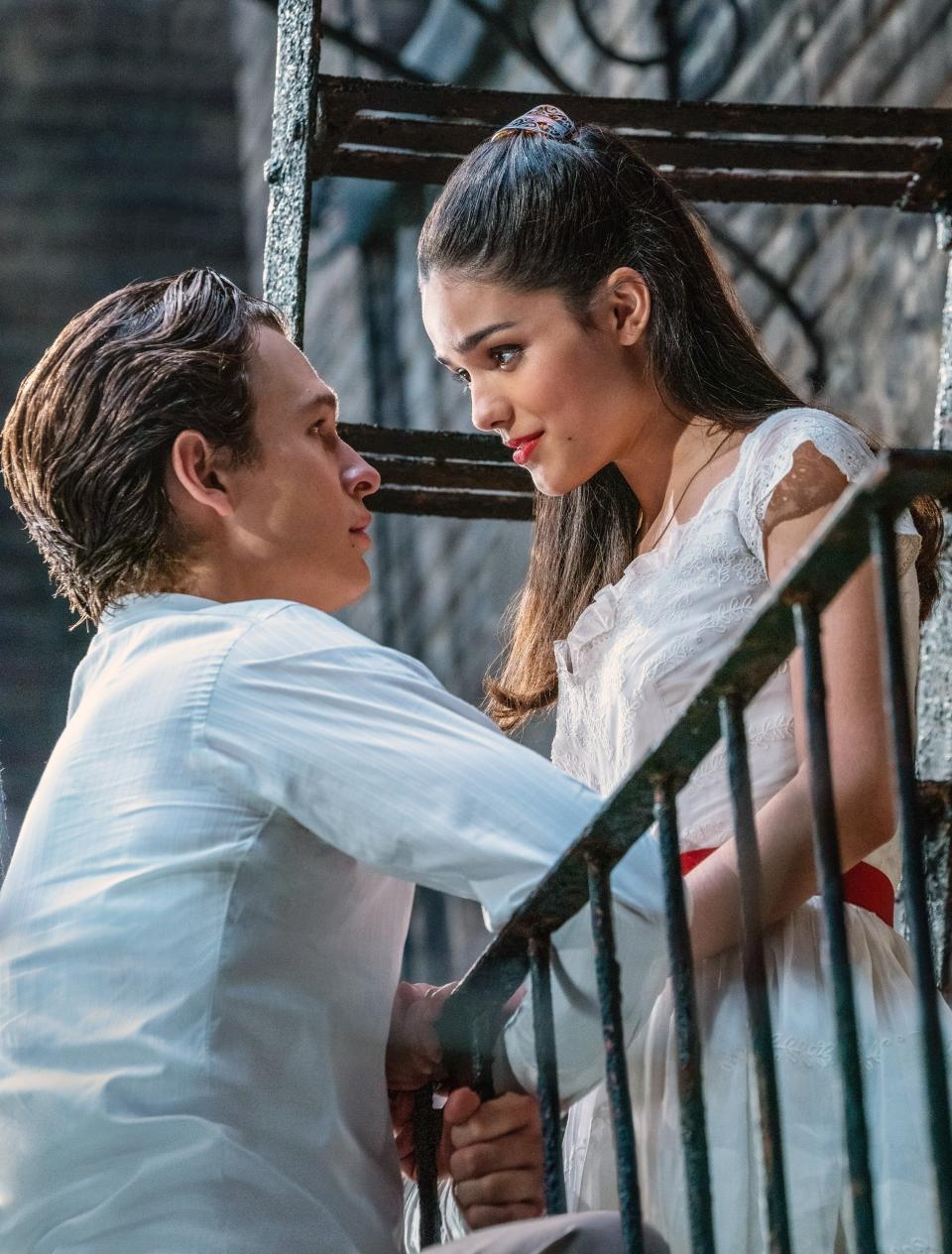 Tony and Maria from West Side Story gaze into each other's eyes on a fire escape. Maria wears a white dress and Tony, a white shirt