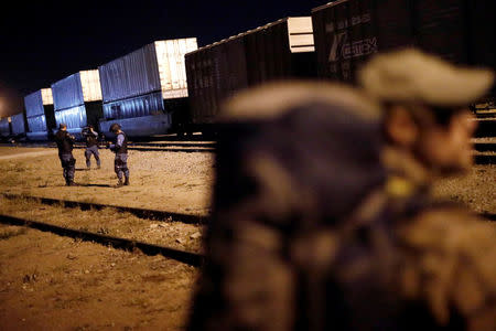 Security guards keep watch as a Central American migrant, moving in a caravan through Mexico, waits next to a railway line before embarking on a new leg of his travels, in Tlaquepaque, in Jalisco state, Mexico April 19, 2018. REUTERS/Edgard Garrido