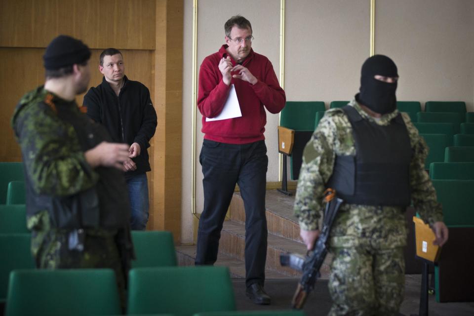 CAPTION CORRECTION, CORRECTS TO REMOVE REFERENCE TO AXEL SCHNEIDER OF GERMANY, MAN AT SECOND RIGHT IS UNIDENTIFIED - Foreign military observers are escorted by pro-Russian militants to attend a press conference in city hall, of Slovyansk, eastern Ukraine, Sunday, April 27, 2014. As Western governments vowed to impose more sanctions against Russia and its supporters in eastern Ukraine, a group of foreign military observers remained in captivity Saturday accused of being NATO spies by a pro-Russian insurgency. The German-led, eight-member team was traveling under the auspices of the Organization of Security and Cooperation in Europe when they were detained Friday. (AP Photo/Alexander Zemlianichenko)