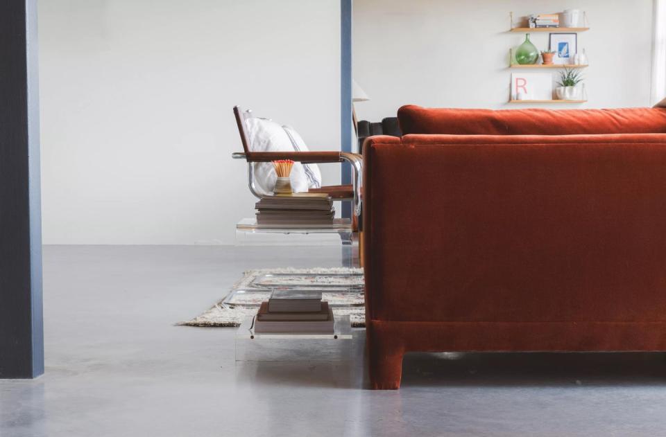 a red couch and a table in a living room with a white blue paint on the walls