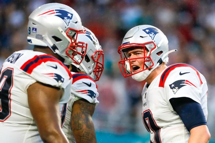 New England Patriots quarterback Mac Jones (10) reacts toward running back Brandon Bolden (25) and guard Shaq Mason (69) after throwing a touchdown pass on Jan. 9, 2022, against the Miami Dolphins in Miami.