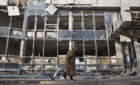 A woman pulls her shopping trolley as she walks past a building that was damaged by shelling in Donetsk, eastern Ukraine in this October 15, 2014 file photo. It may have looked in the West like Russian President Vladimir Putin fled this weekend's G20 summit early with his tail between his legs after being berated over Ukraine. But it was a different story in Russia, where pliant media praised Putin for being courageous enough to "enter the lion's den", stand up to his critics and defend national interests, and accepted his excuse that he faced a long trip home. State television said the G20 had gone better for Putin than Western media had predicted and that U.S. President Barack Obama was the leader left isolated by two summits in a week. REUTERS/Shamil Zhumatov/Files (UKRAINE - Tags: CIVIL UNREST POLITICS)