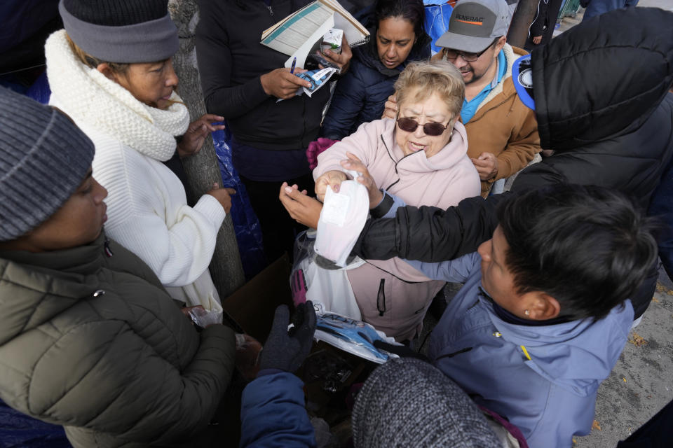 Esmeralda Jimenez, from Waukegan, Ill., hands out clothing to migrants at a small tent community, Wednesday, Nov. 1, 2023, near a Northside police station in Chicago. (AP Photo/Charles Rex Arbogast)