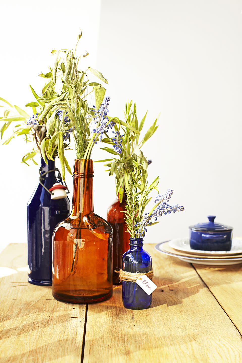 <p>Scour your local flea market for blue and amber glass vessels. Fill some with flowers or herbs — leftover sage from the kitchen fits the theme — and use the smaller ones as place cards. </p>