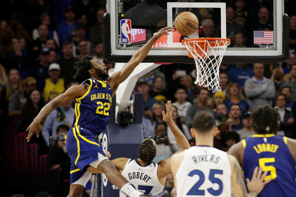 Golden State Warriors forward Andrew Wiggins (22) dunks over Minnesota Timberwolves center Rudy Gobert (27) during the first quarter of an NBA basketball game Sunday, Nov. 27, 2022, in Minneapolis. (AP Photo/Andy Clayton-King)