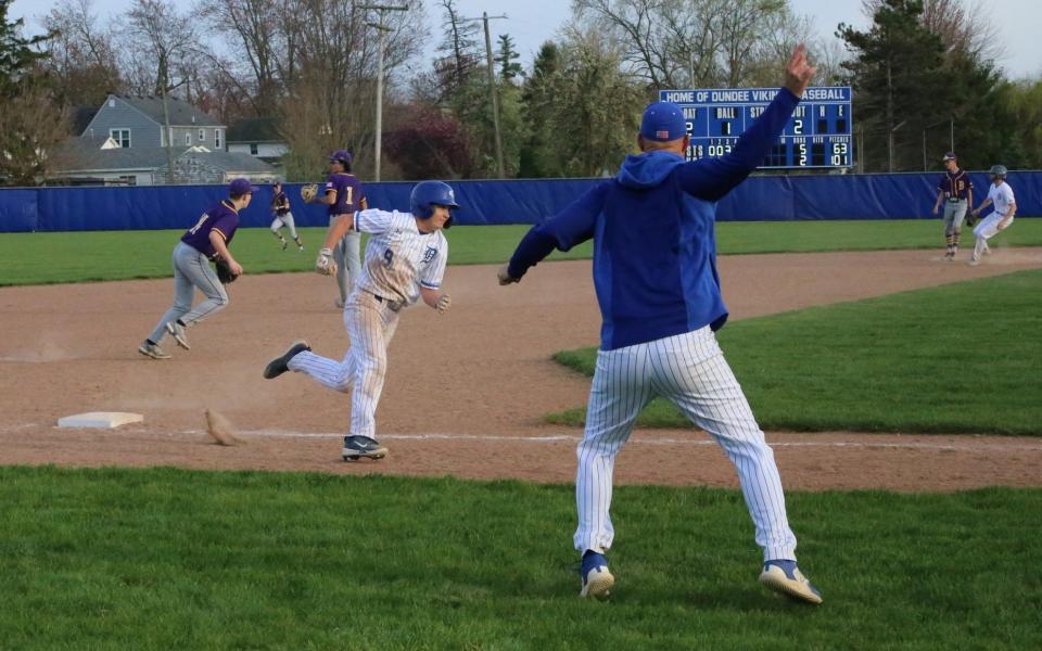 Dundee baseball coach Paul Walters waves home Ashton Viers during a split with Blissfield on Tuesday, April 16, 2024.