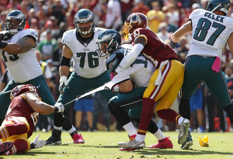 <p>Philadelphia Eagles quarterback Carson Wentz’s jersey tears as he is tackled by Washington Redskins outside linebacker Ryan Kerrigan, left, and free safety Will Blackmon in the first half of an NFL football game, Sunday, Oct. 16, 2016, in Landover, Md. (AP Photo/Alex Brandon) </p>