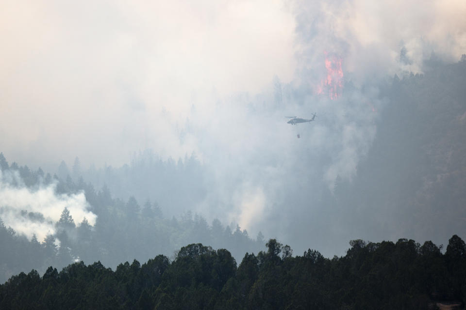 This photo taken Aug. 6, 2018, shows a helicopter heads out to dump water on the Coal Hollow Fire near U.S. Highway 6. An Idaho prisoner sent to help fight a wildfire in Utah raped a woman who also was working to support firefighters, prosecutors said Tuesday, Sept. 4, 2018. The woman had rejected several advances from Ruben Hernandez, 27, in the days before the Aug. 29 assault at the base camp, Sanpete County attorney Kevin Daniels said. Hernandez has been charged with felony rape. (Evan Cobb/The Daily Herald via AP)