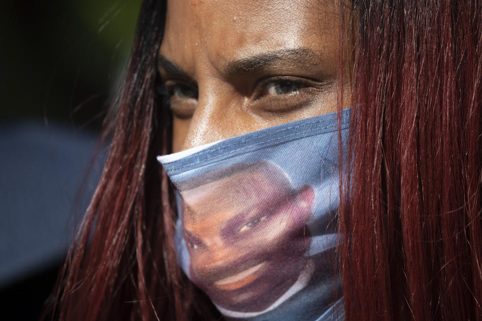 FILE- In this May 8, 2020 file photo, a woman wears a face covering with the likeness of shooting victim Ahmaud Arbery printed on it during a rally to protest Arbery's killing, in Brunswick Ga. T. Georgia’s attorney general has asked the U.S. Department of Justice to investigate the handling of the killing of Ahmaud Arbery. Authorities say Arbery, a black man, died at the hands of two white men in February near the coastal city of Brunswick as he ran through a neighborhood. (AP Photo/John Bazemore, File)