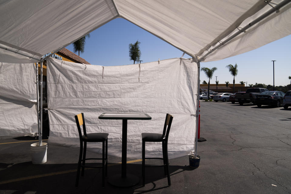 FILE - In this Sept. 30, 2020 file photo, a table, and chairs are set up in the outdoor dining area of a restaurant at a strip mall in La Mirada, Calif. California's financially battered restaurants filed government claims Monday to recover more than $100 million in fees for liquor and health permits and tourism charges that they say were assessed even though their businesses were shuttered or only partially operating under long-running coronavirus orders. Few industries have been hit as hard during the pandemic as restaurants. (AP Photo/Jae C. Hong, File)