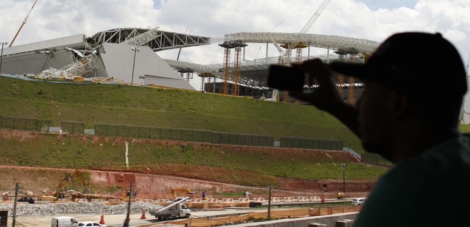 A man takes a picture of a crane that collapsed on the site of the Arena Sao Paulo stadium, known as "Itaquerao", which will host the opening soccer match of the 2014 World Cup, in Sao Paulo