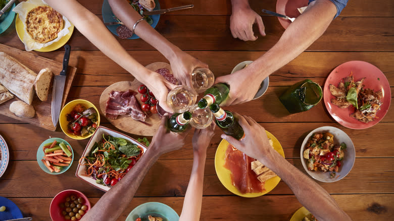 Hands toasting beer over food