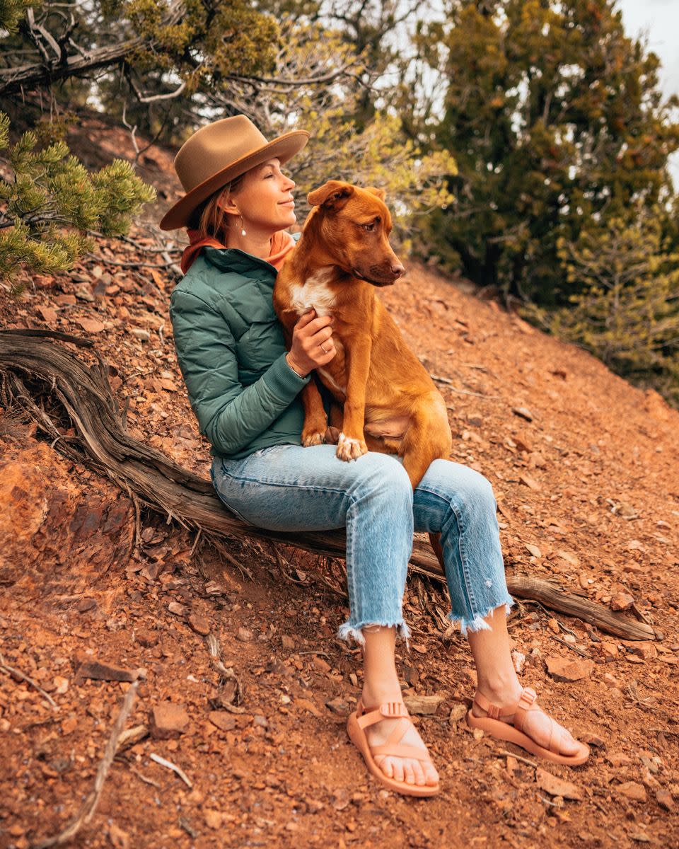 sarah herron with her dog, sitting down in woodsy area