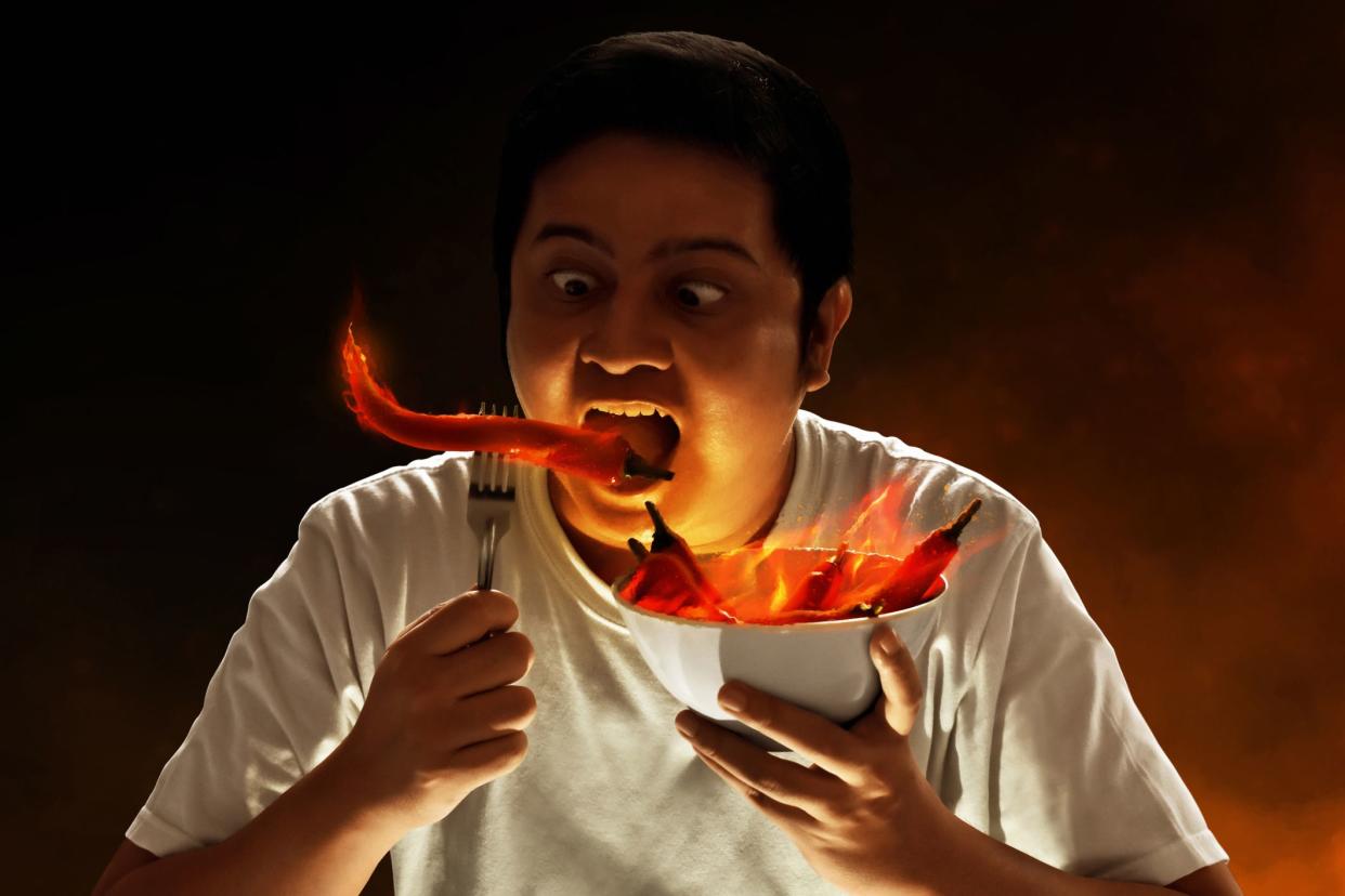 Portrait of young man eating chili pepper