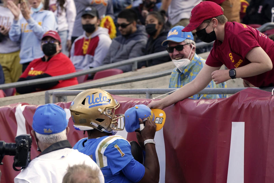 UCLA quarterback Dorian Thompson-Robinson, left, signs a hat for a fan after scoring a touchdown during the first half of an NCAA college football game against Southern California Saturday, Nov. 20, 2021, in Los Angeles. (AP Photo/Mark J. Terrill)