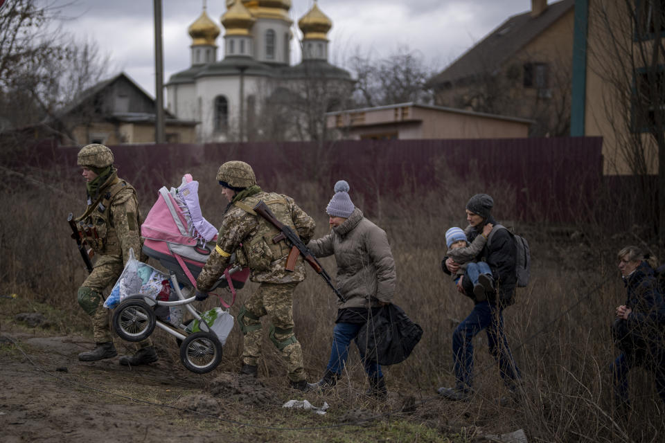 Ukrainian soldiers help a fleeing family crossing the Irpin river on the outskirts of Kyiv, Ukraine, Saturday, March 5, 2022. (AP Photo/Emilio Morenatti)