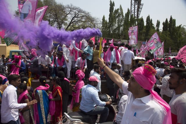 A supporter of Telangana Rashtra Samithi, a regional political party, sprays colour as he participates with others in an election campaign rally in Hyderabad