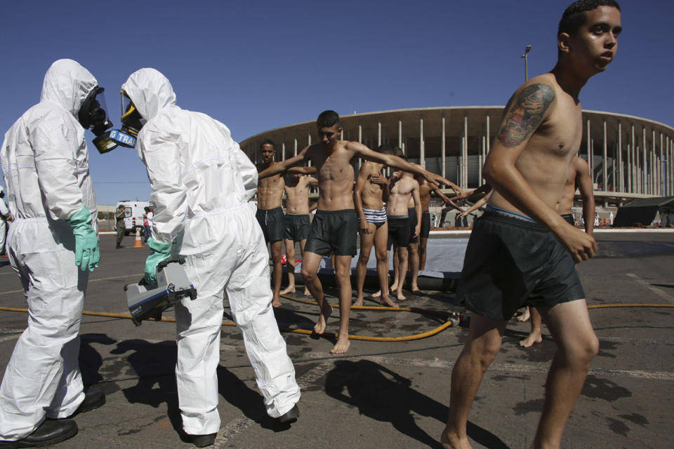 <p>A soldier dressed in a hazmat suit holds a machine that reads radiation levels, during the practice of a decontamination plan against a chemical attack, outside the National Stadium, which will host the 2016 Summer Olympics soccer matches in Brasilia, Brazil, July 28, 2016. (Photo: Eraldo Peres/AP)</p>