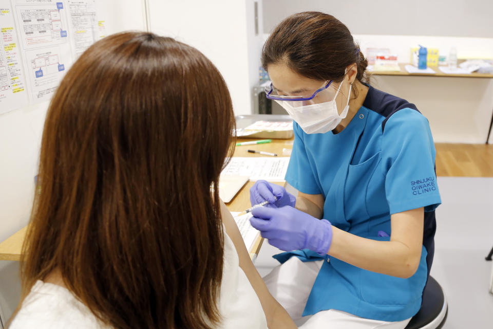 A medical worker gets Moderna's COVID-19 vaccine at an inoculation site set up by Japanese technology company SoftBank Group Corp. at a WeWork office Tuesday, June 15, 2021, in Tokyo. Japanese companies have joined the effort to speed up the country’s lagging coronavirus vaccine rollout before the Tokyo Olympics begin next month. (AP Photo/Yuri Kageyama)