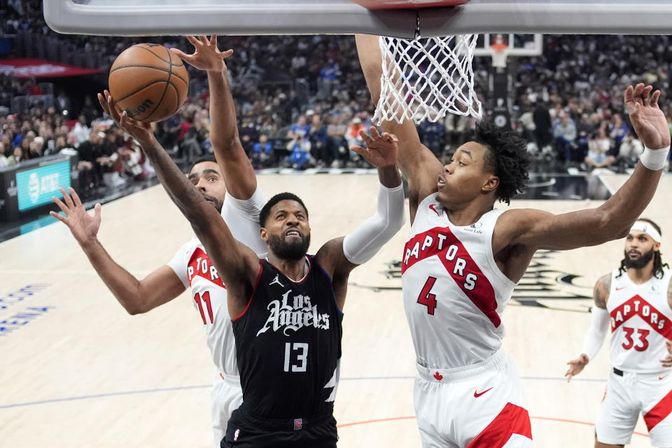 Los Angeles Clippers forward Paul George, center shoots as Toronto Raptors center Jontay Porter, left, and forward Scottie Barnes defend during the second half of an NBA basketball game Wednesday, Jan. 10, 2024, in Los Angeles. (AP Photo/Mark J. Terrill)