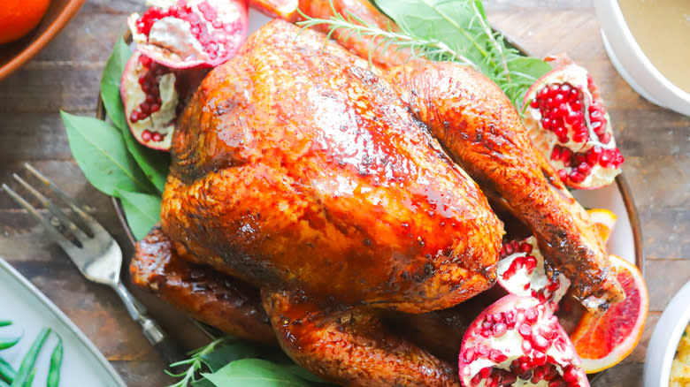 Smoked and glazed Thanksgiving turkey on plate with pomegranates