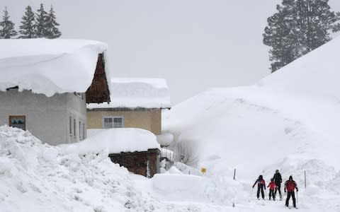 Skiers make their way through the streets after heavy snowfall in the small village of Filzmoos, Austria - Credit: Christof Stache/AFP