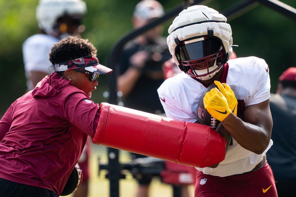 Washington Commanders assistant running backs coach Jennifer King attempts to knock the ball away from running back Antonio Gibson during an NFL football practice at the team's training facility, Wednesday, Aug. 2, 2023, in Ashburn, Virginia