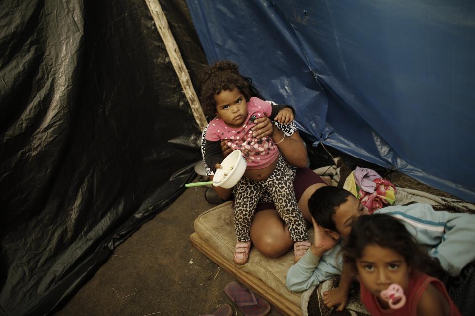 A family of Brazil's Homeless Workers' Movement (MTST) sits in a newly built shack at the "People's World Cup" camp, which houses an estimate of 2,800 families of the movement, in the district of Itaquera near Sao Paulo's World Cup stadium, in Sao Paulo May 7, 2014. For Sao Paulo's most popular soccer team, the World Cup has provided a new home after 100 years playing in rented stadiums. Thousands of neighbors, however, say it has left them homeless. They are squatting on land a couple miles south of Arena Corinthians, a glistening white stadium built for nearly 1 billion reais ($450 million) to host six games during the tournament, including the opening match in less than a month. Picture taken May 7, 2014. To match Feature BRAZIL-WORLDCUP/SAOPAULO REUTERS/Nacho Doce (BRAZIL - Tags: SPORT SOCCER WORLD CUP SOCIETY POVERTY)