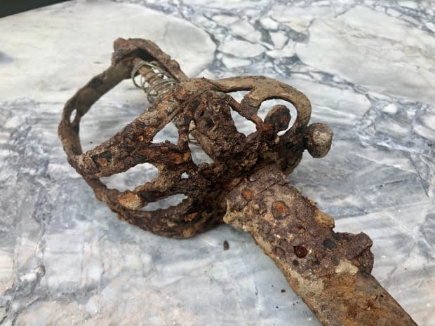 The sword's ornate hand guard is heavily corroded and, according to one expert, bent. Certain details date the sword to no earlier than 1897. (Alistair Steele/CBC - image credit)