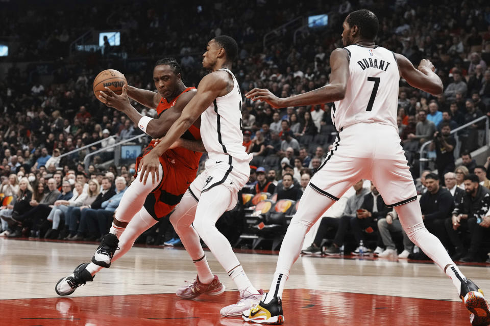 Toronto Raptors forward O.G. Anunoby (3) drives as Brooklyn Nets forward Nic Claxton (33) and forward Kevin Durant (7) defend during the first half of an NBA basketball game Wednesday, Nov. 23, 2022, in Toronto. (Chris Young/The Canadian Press via AP)