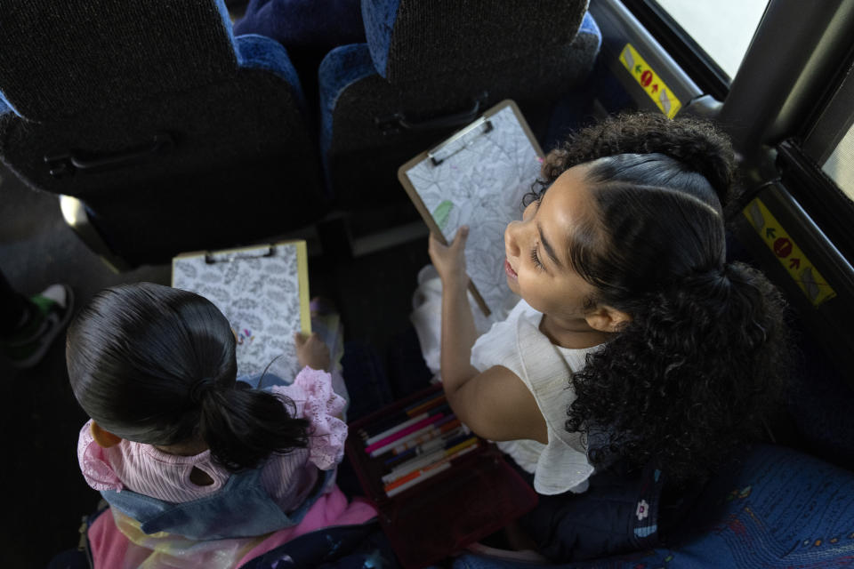 Accompanied by their grandmother Raquel Ayala and three other siblings, Jaliyah Santiago, 4, left, and her sister Myla Martinez, 6, color as they ride a bus on a three-hour journey to Logan Correctional Center in downstate Illinois to their incarcerated mother Crystal Martinez, Saturday, May 20, 2023, in Illinois. Rare programs like the Reunification Ride, a donation-dependent initiative that buses prisoners' family members from Chicago to Illinois' largest women's prison every month so they can spend time with their mothers and grandmothers, are a crucial lifeline for families, prisoners say. (AP Photo/Erin Hooley)