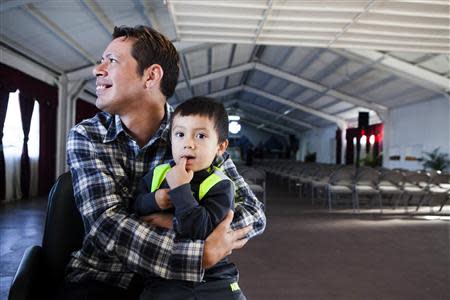 David Amaya holds 3-year-old Isaac Moreno, a young boy in daycare at Iglesia de Cristo Ministerios Llamada Final in San Diego, California November 24, 2013. REUTERS/Sam Hodgson