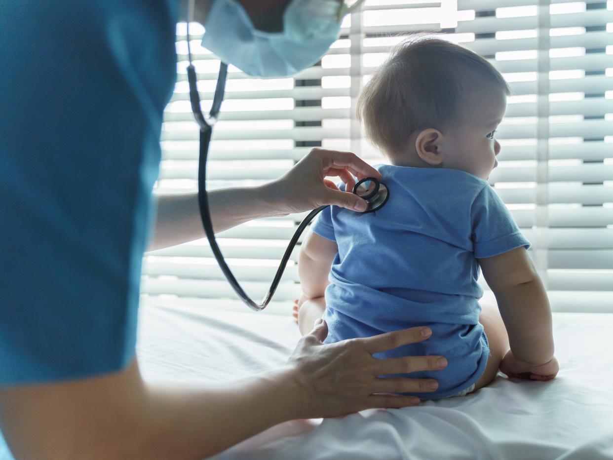 female Pediatrician doctor examining her little baby patient with stethoscope in medical room