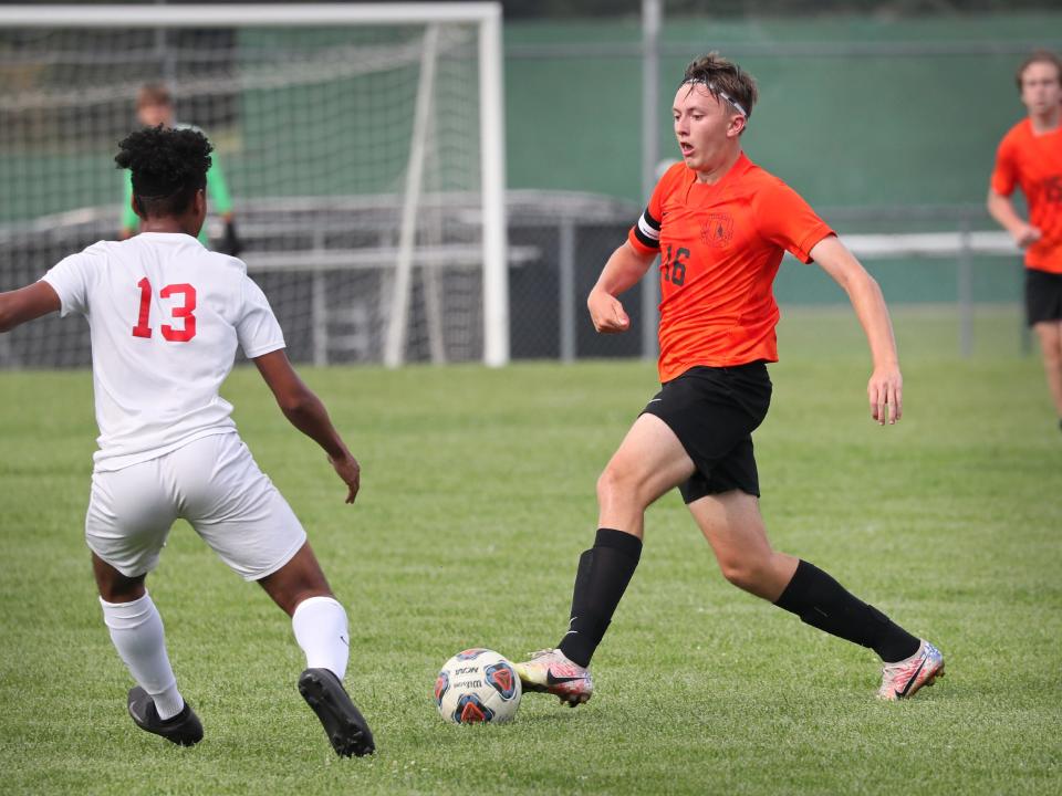 Tecumseh senior midfielder Ryan Somsel (16) dribbles the ball against Dearborn Divine Child's Dejai Robinson (13) during the first half of their game Wednesday afternoon.