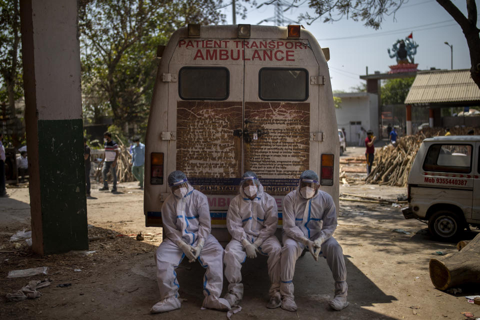 Exhausted workers, who bring dead bodies for cremation, sit on the rear step of an ambulance inside a crematorium, in New Delhi, India, Saturday, April 24, 2021. Delhi has been cremating so many bodies of coronavirus victims that authorities are getting requests to start cutting down trees in city parks, as a second record surge has brought India's tattered healthcare system to its knees. (AP Photo/Altaf Qadri)