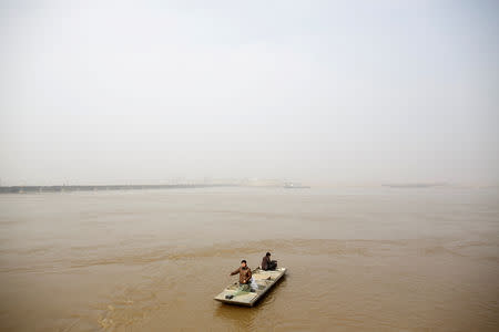 FILE PHOTO: Fishermen travel down the Yellow River to cast their net on the northern outskirts of Zhengzhou, Henan province, China, February 21, 2019. REUTERS/Thomas Peter/File Photo